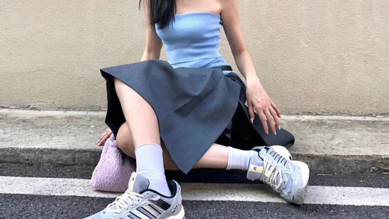 Cô gái sành điệu mặc chân váy xòe xếp ly phối giày sneaker độn đế màu trắng
