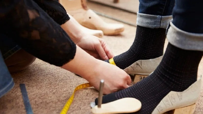 Hình ảnh một người đang đo chiều dài bàn chân trên tờ giấy
