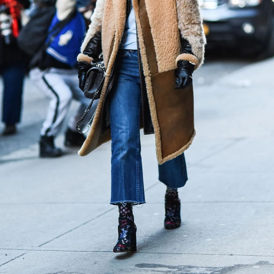 Một cô gái sành điệu mặc quần ống loe denim, kết hợp cùng đôi boots cổ thấp màu nâu, thể hiện phong cách cá tính và ấm áp cho mùa lạnh